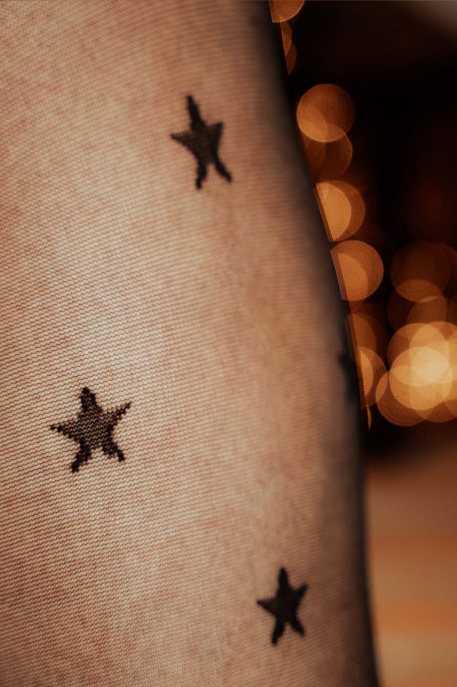 Plussize-Strumpfhose Sternchen-Muster in Nahaufnahme. Das Muster ist eingewebt, nicht aufgedruckt mit schwarzen Sternen auf transparent-schwarzen Strumpfhosen.